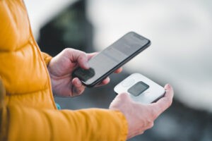 Hands holding smartphone and portable WiFi hotspot device.