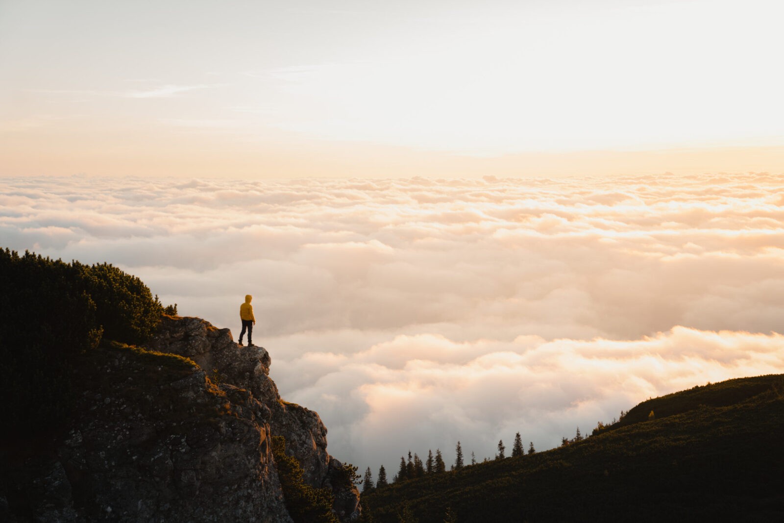 Majestic mountain scenery with hiker above a sea of clouds.