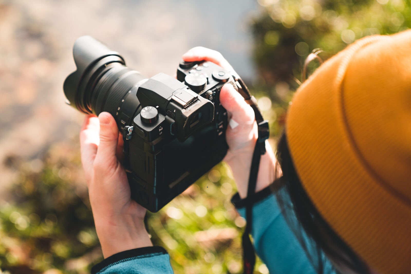 Close-up of hands holding camera with dials and buttons.