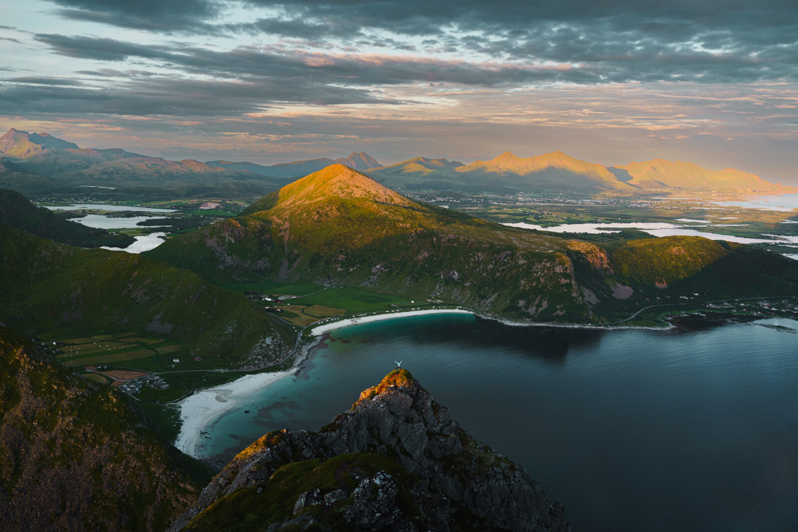 Aerial view of a secluded white sand beach with turquoise water and mountains.